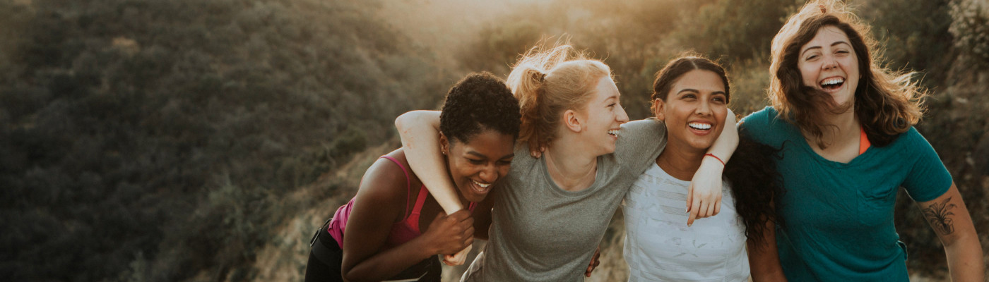 Health category background image depicting 4 young women smiling on a hike.